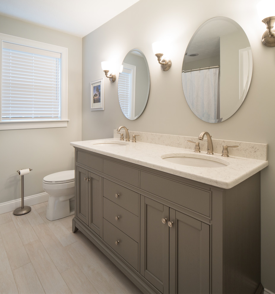 Photo of a mid-sized transitional bathroom in Boston with grey cabinets, a one-piece toilet, an undermount sink, recessed-panel cabinets, white tile, porcelain tile, grey walls, porcelain floors and engineered quartz benchtops.