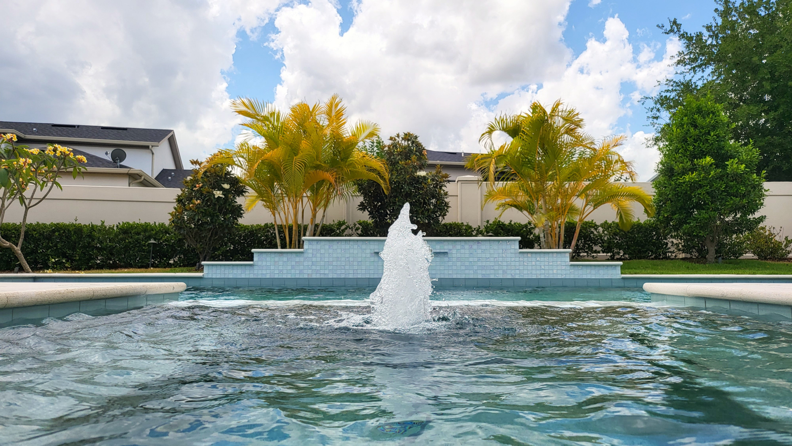 Beautiful modern pool and spa with water feature in Orlando, Florida.  Featuring Pebbletec Caribbean Blue interior and Artistic pavers.