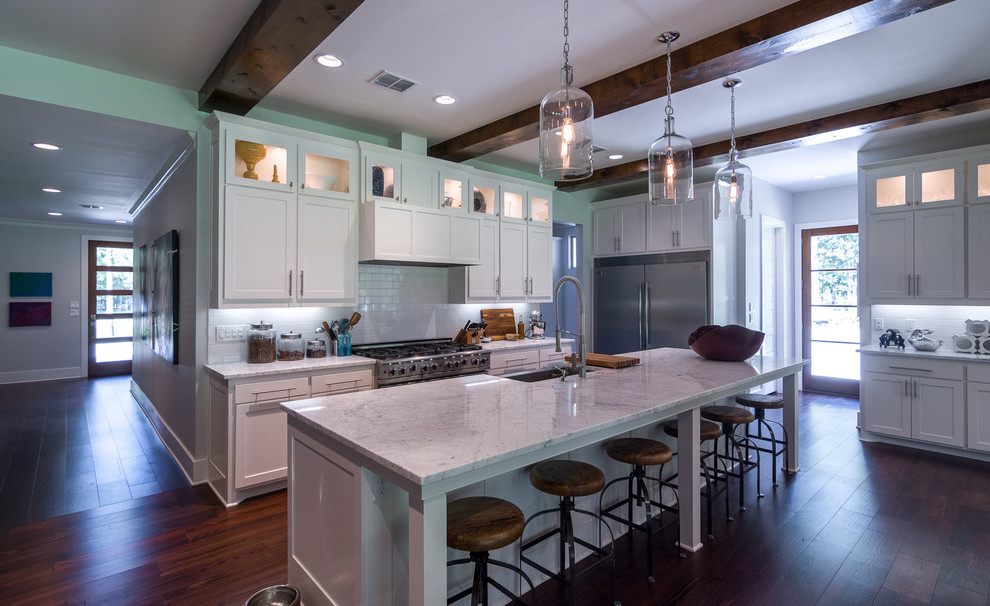 This is an example of an expansive contemporary kitchen in New Orleans with white cabinets, marble benchtops, white splashback and stainless steel appliances.