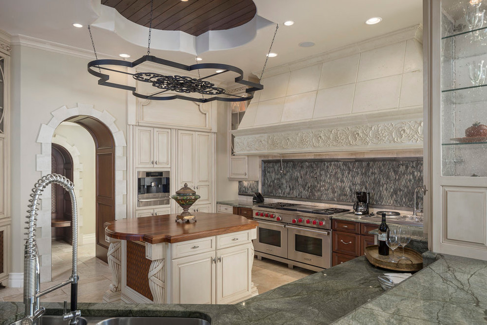 Inspiration for a large mediterranean u-shaped separate kitchen in Orlando with an undermount sink, raised-panel cabinets, white cabinets, quartzite benchtops, grey splashback, stainless steel appliances, travertine floors, with island and beige floor.