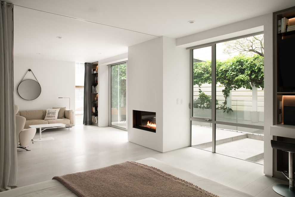 Design ideas for a large modern open concept living room in San Francisco with white walls, light hardwood floors, a standard fireplace, a plaster fireplace surround and beige floor.