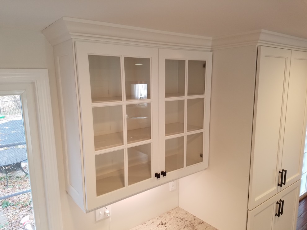 Inspiration for a mid-sized transitional l-shaped dark wood floor and brown floor eat-in kitchen remodel with a farmhouse sink, shaker cabinets, white cabinets, granite countertops, white backsplash, subway tile backsplash, stainless steel appliances and an island