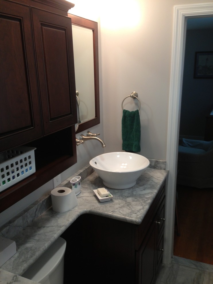 Inspiration for a small transitional 3/4 gray tile, white tile and porcelain tile porcelain tile doorless shower remodel in Baltimore with raised-panel cabinets, dark wood cabinets, a two-piece toilet, white walls, a vessel sink and quartzite countertops
