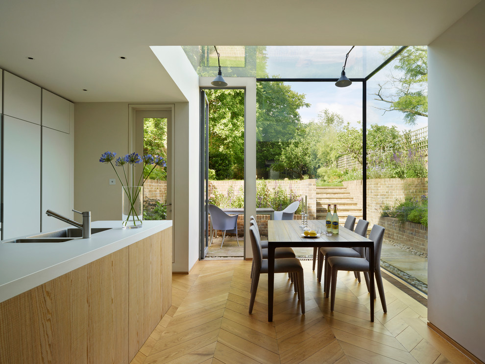 Photo of a modern kitchen/dining combo in London with white walls and light hardwood floors.