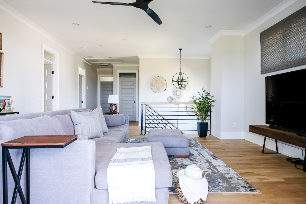 This is an example of a mid-sized beach style open concept family room in Charleston with grey walls, light hardwood floors and a wall-mounted tv.
