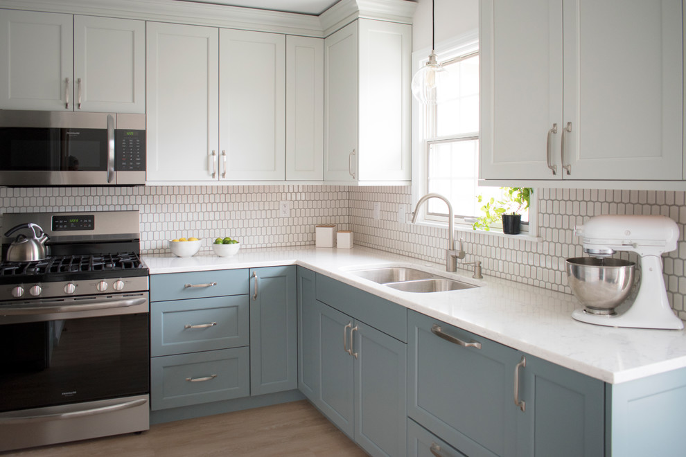 Mid-sized transitional l-shaped light wood floor and beige floor eat-in kitchen photo in Chicago with an undermount sink, shaker cabinets, quartz countertops, white backsplash, mosaic tile backsplash, stainless steel appliances, no island, white countertops and blue cabinets