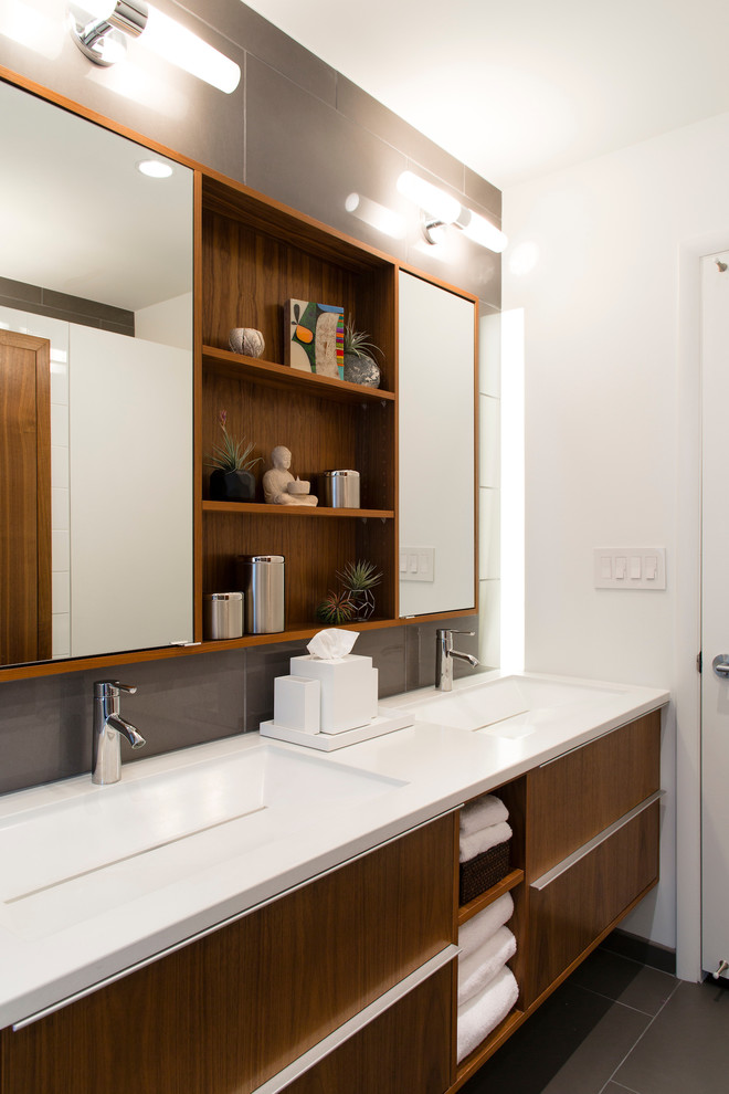 Mid-sized midcentury kids bathroom in Omaha with furniture-like cabinets, dark wood cabinets, a drop-in tub, a shower/bathtub combo, a one-piece toilet, gray tile, porcelain tile, white walls, porcelain floors, an integrated sink and concrete benchtops.
