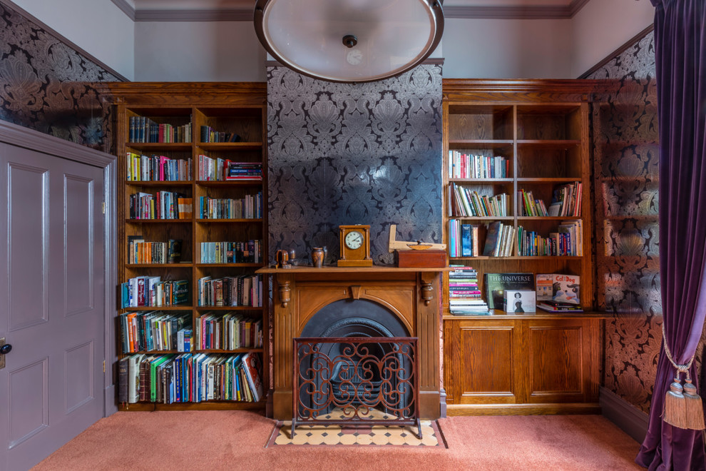 This is an example of a mid-sized traditional study room in Melbourne with grey walls, carpet, a standard fireplace, a wood fireplace surround, a freestanding desk and orange floor.