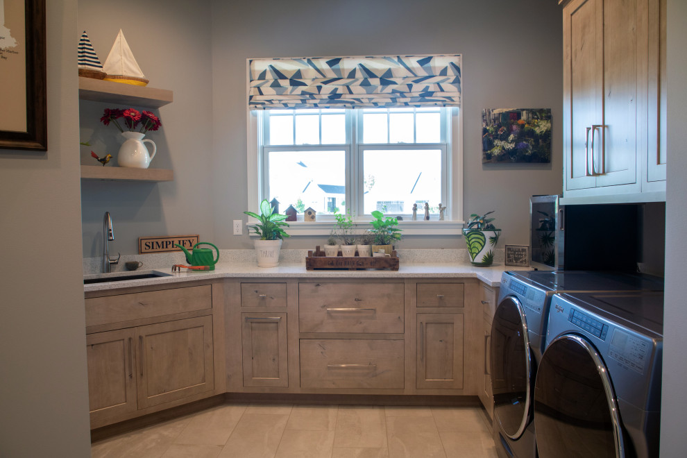 Design ideas for a large transitional u-shaped dedicated laundry room in Milwaukee with an undermount sink, recessed-panel cabinets, distressed cabinets, quartz benchtops, grey walls, porcelain floors, a side-by-side washer and dryer, beige floor and multi-coloured benchtop.