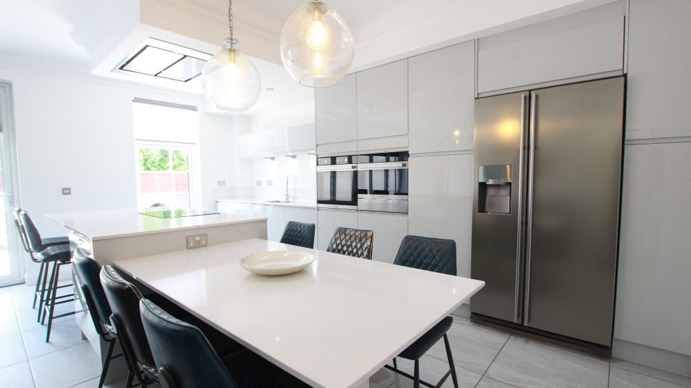 Inspiration for a large contemporary galley open plan kitchen in Glasgow with an integrated sink, flat-panel cabinets, grey cabinets, quartzite benchtops, white splashback, granite splashback, black appliances, porcelain floors, with island, grey floor, white benchtop and recessed.