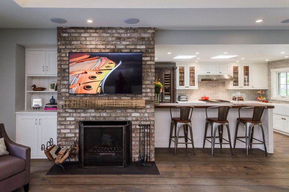 Inspiration for a large transitional open concept living room in San Francisco with grey walls, dark hardwood floors, a standard fireplace, a brick fireplace surround and a wall-mounted tv.
