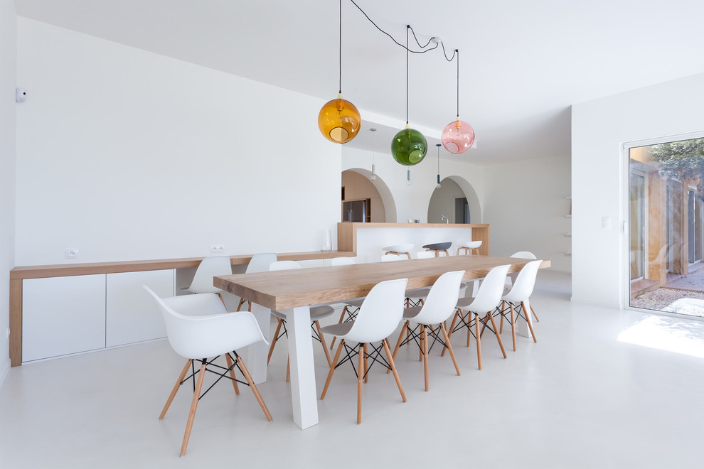Expansive scandinavian open plan dining in Paris with white walls, concrete floors and white floor.