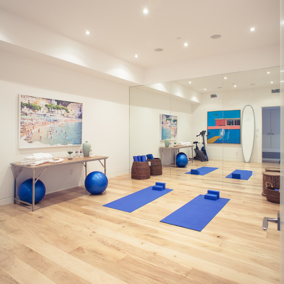 This is an example of a large contemporary multipurpose gym in Los Angeles with white walls and medium hardwood floors.