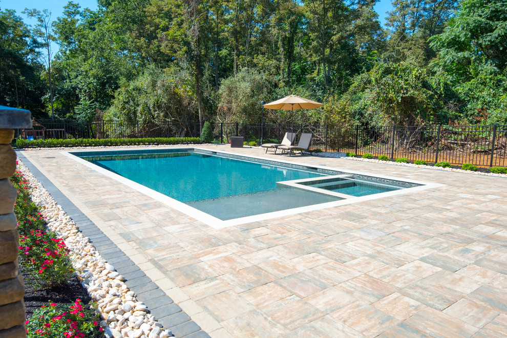 Photo of a large modern backyard rectangular lap pool in New York with a hot tub and brick pavers.