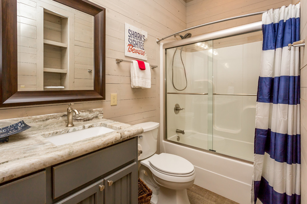 This is an example of a beach style bathroom in Miami with grey cabinets, an open shower, brown tile, beige walls, granite benchtops and an undermount sink.
