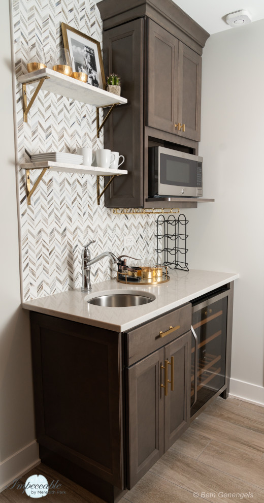 Inspiration for a small transitional single-wall wet bar in Chicago with an undermount sink, flat-panel cabinets, brown cabinets, quartz benchtops, multi-coloured splashback, glass tile splashback, porcelain floors, brown floor and grey benchtop.