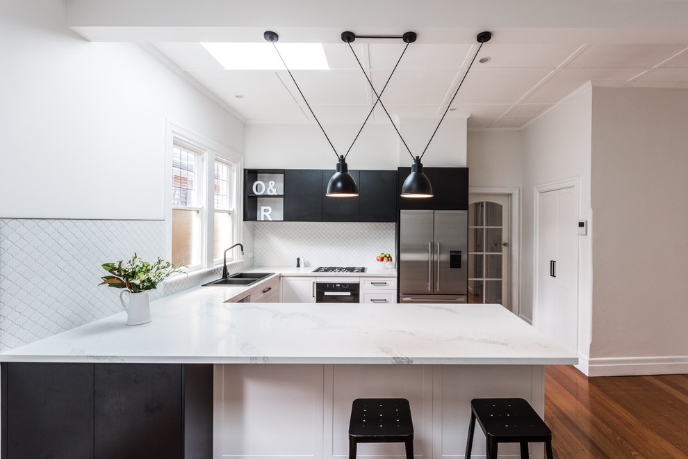 Inspiration for a contemporary u-shaped kitchen in Melbourne with a double-bowl sink, flat-panel cabinets, black cabinets, marble benchtops, white splashback, stainless steel appliances, medium hardwood floors and a peninsula.