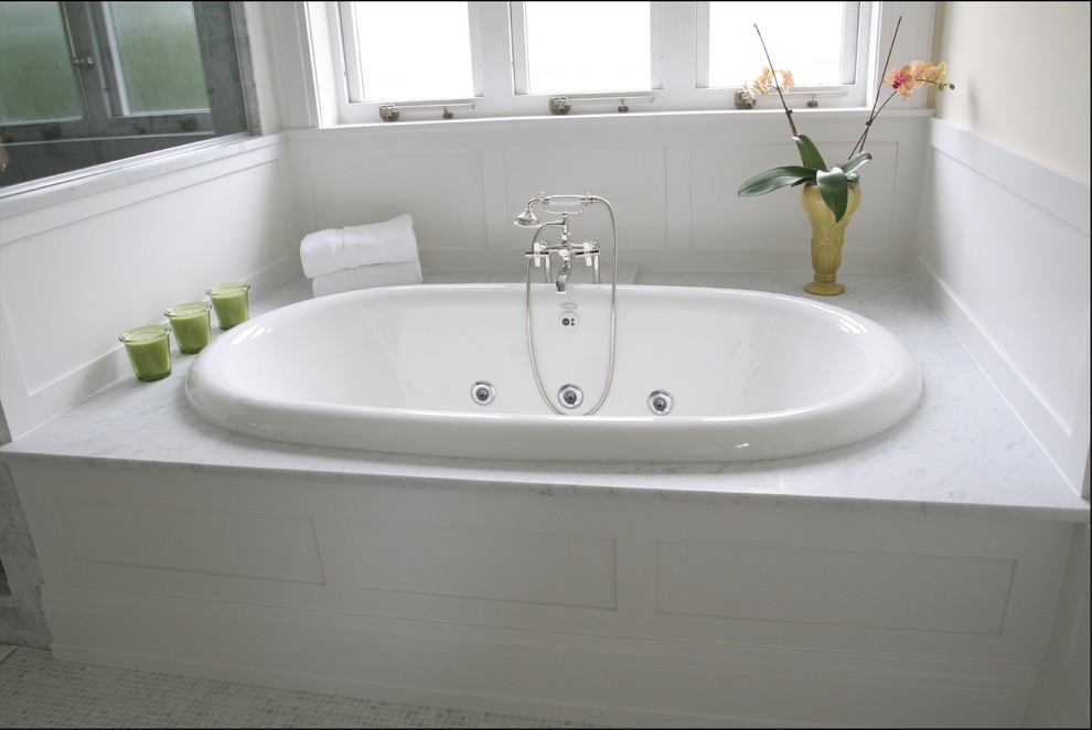 Inspiration for a mid-sized transitional white tile and mosaic tile marble floor drop-in bathtub remodel in Minneapolis with an undermount sink, shaker cabinets, white cabinets, marble countertops, a two-piece toilet and beige walls
