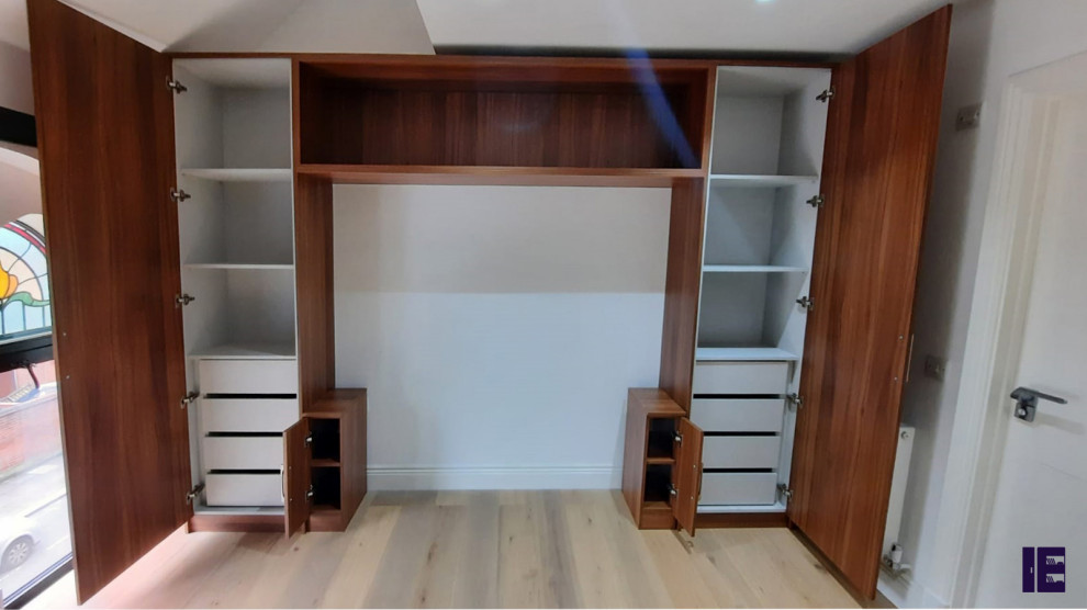 This is an example of a small modern built-in wardrobe in London with flat-panel cabinets, brown cabinets and plywood floors.