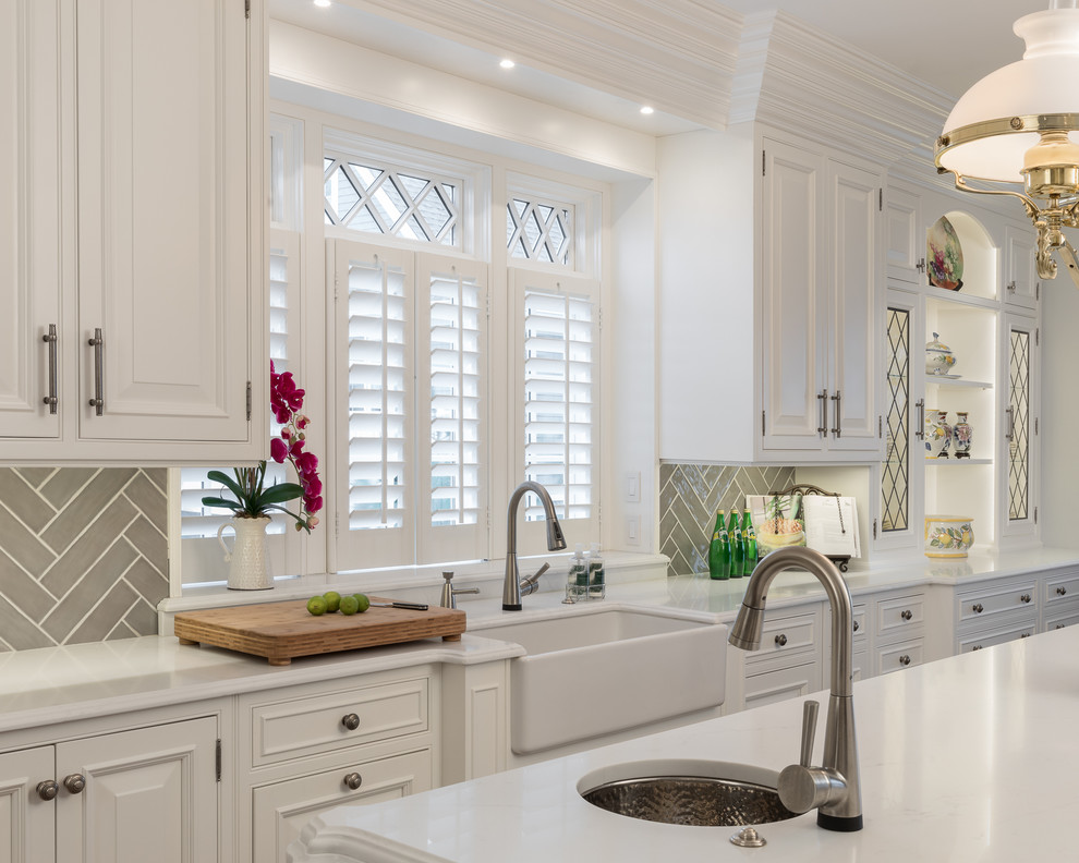 Inspiration for a huge transitional u-shaped medium tone wood floor and brown floor open concept kitchen remodel in Newark with a farmhouse sink, raised-panel cabinets, white cabinets, quartz countertops, gray backsplash, ceramic backsplash, white appliances, an island and white countertops