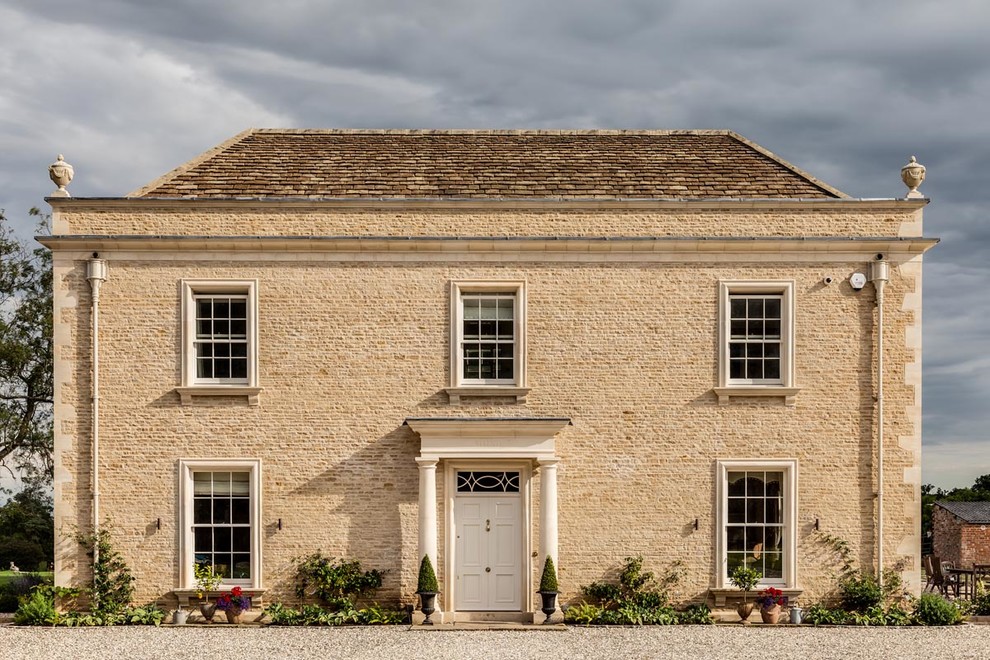 Traditional beige house exterior in Gloucestershire with stone veneer and a gable roof.