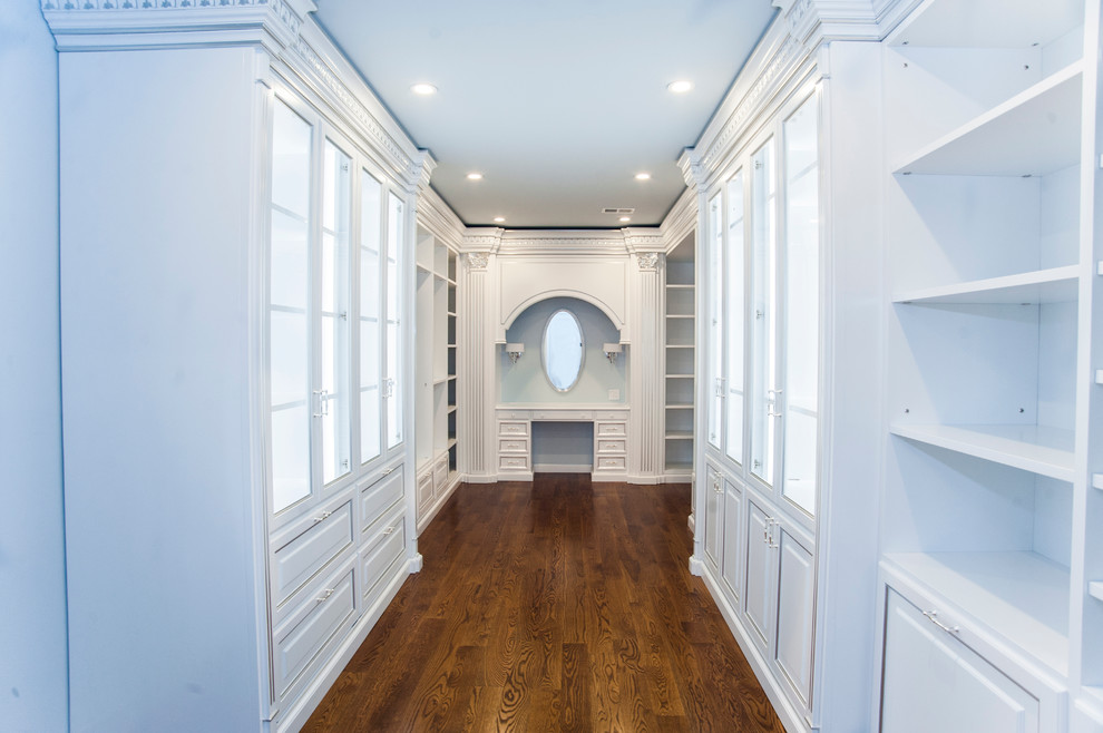 This is an example of a large mediterranean women's walk-in wardrobe in DC Metro with glass-front cabinets, white cabinets and medium hardwood floors.