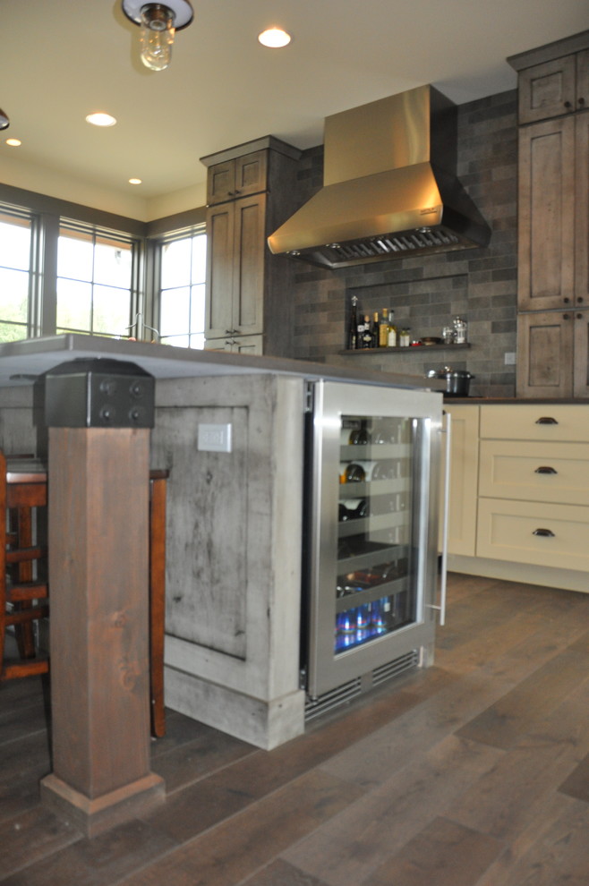 Example of a large mountain style l-shaped medium tone wood floor eat-in kitchen design in Seattle with an undermount sink, shaker cabinets, distressed cabinets, quartz countertops, gray backsplash, stone tile backsplash, stainless steel appliances and an island