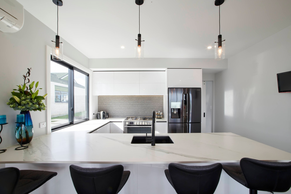 Idéer för mellanstora funkis vitt kök, med vita skåp, marmorbänkskiva, grått stänkskydd, rostfria vitvaror, marmorgolv, en köksö och brunt golv