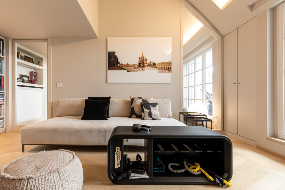 Modern inredning av ett vardagsrum, med vita väggar, ljust trägolv, en väggmonterad TV och beiget golv