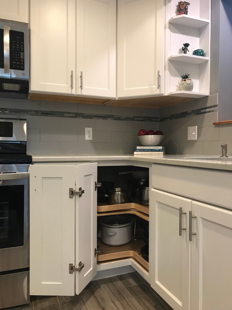 Example of a mid-sized transitional l-shaped porcelain tile and gray floor open concept kitchen design in Boston with a single-bowl sink, flat-panel cabinets, white cabinets, quartz countertops, gray backsplash, subway tile backsplash, stainless steel appliances, an island and white countertops