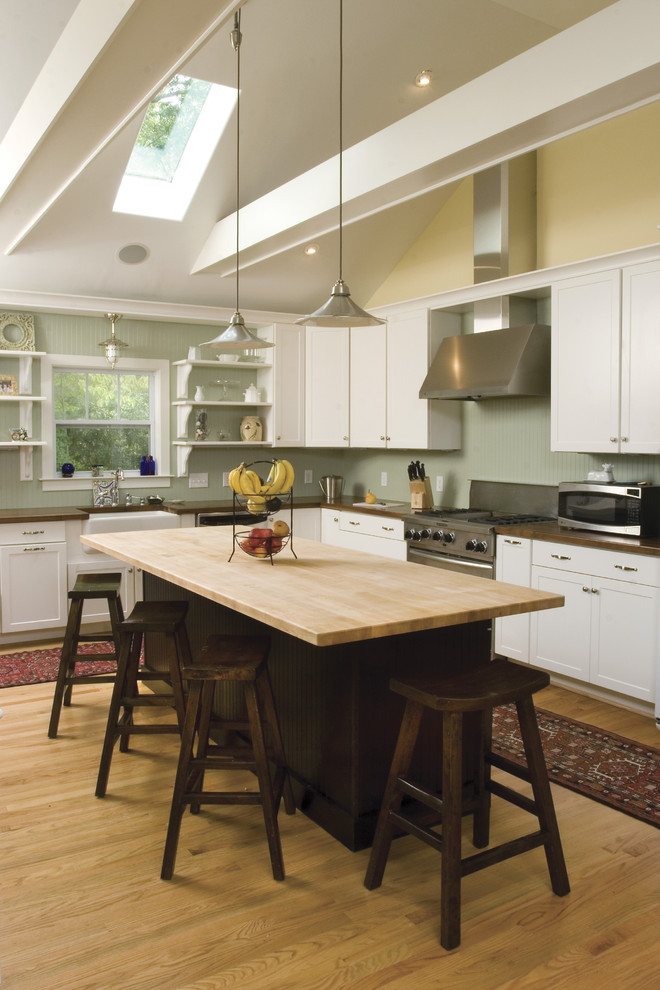 Transitional l-shaped kitchen in Other with wood benchtops, a farmhouse sink, shaker cabinets, white cabinets and stainless steel appliances.