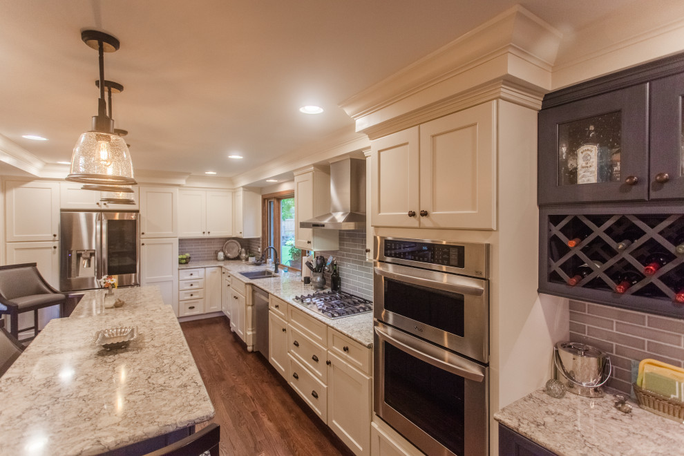 Inspiration for a large transitional single-wall dark wood floor, brown floor and coffered ceiling eat-in kitchen remodel in Cincinnati with a double-bowl sink, shaker cabinets, white cabinets, granite countertops, gray backsplash, subway tile backsplash, stainless steel appliances, an island and multicolored countertops
