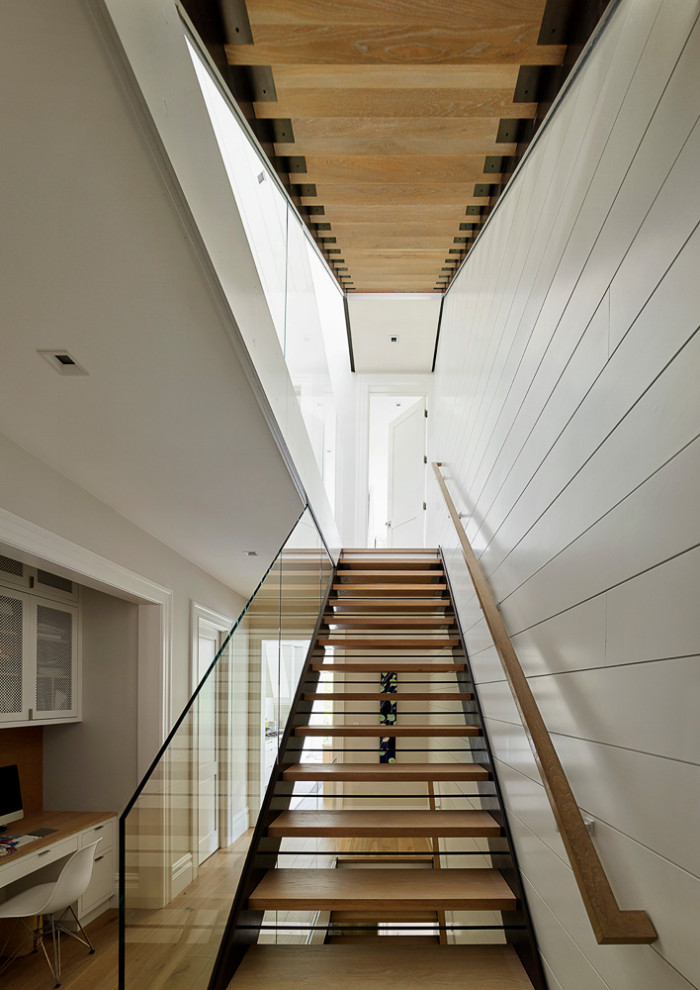 This is an example of a large contemporary wood straight staircase in San Francisco with open risers and glass railing.