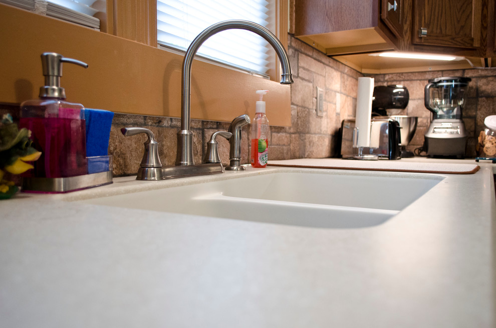 Eat-in kitchen - mid-sized transitional l-shaped vinyl floor eat-in kitchen idea in Chicago with an integrated sink, recessed-panel cabinets, dark wood cabinets, solid surface countertops, multicolored backsplash, porcelain backsplash, stainless steel appliances and an island