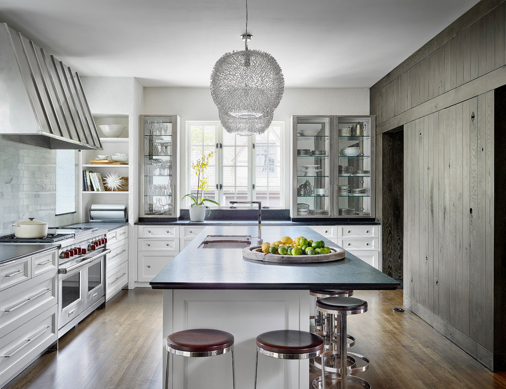 This is an example of a country l-shaped kitchen in Chicago with an undermount sink, recessed-panel cabinets, white cabinets, white splashback, stainless steel appliances, dark hardwood floors and with island.