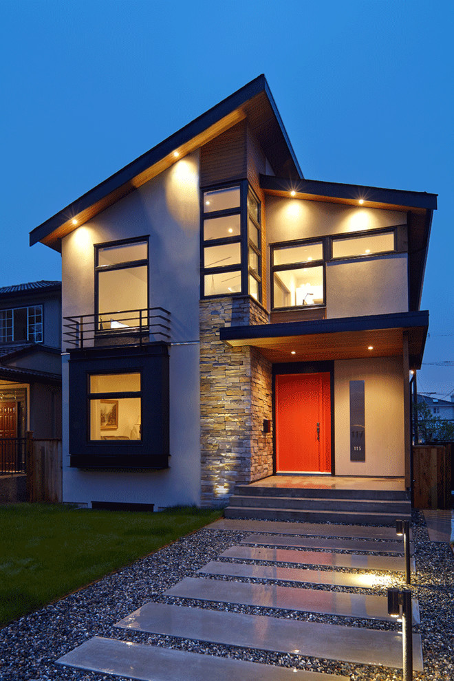 Photo of a mid-sized contemporary two-storey grey house exterior in Vancouver with stone veneer and a shed roof.