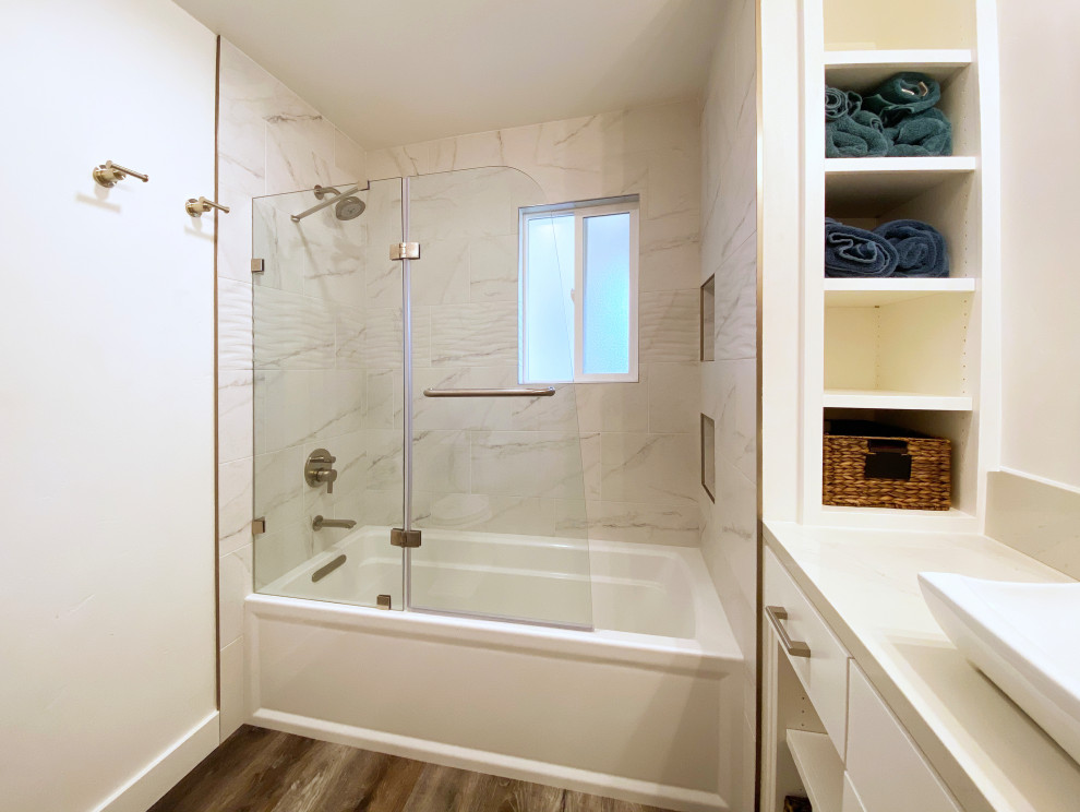 Inspiration for a mid-sized transitional 3/4 black and white tile and porcelain tile vinyl floor, brown floor and single-sink alcove bathtub remodel with shaker cabinets, white cabinets, a two-piece toilet, white walls, a vessel sink, quartz countertops, a hinged shower door, gray countertops, a niche and a built-in vanity