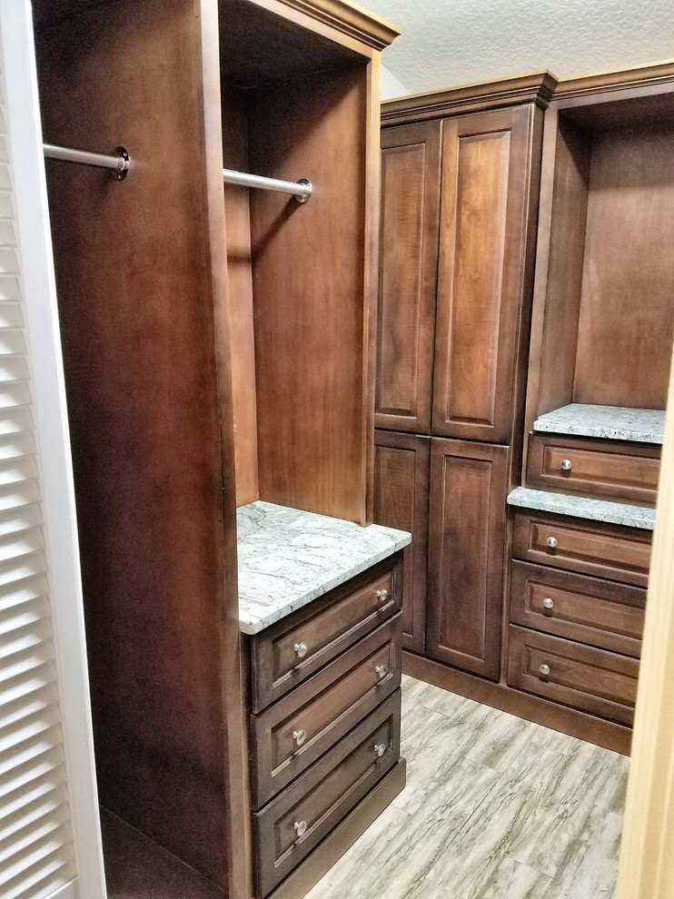Photo of a mid-sized traditional gender-neutral walk-in wardrobe in Orlando with raised-panel cabinets, medium wood cabinets and porcelain floors.