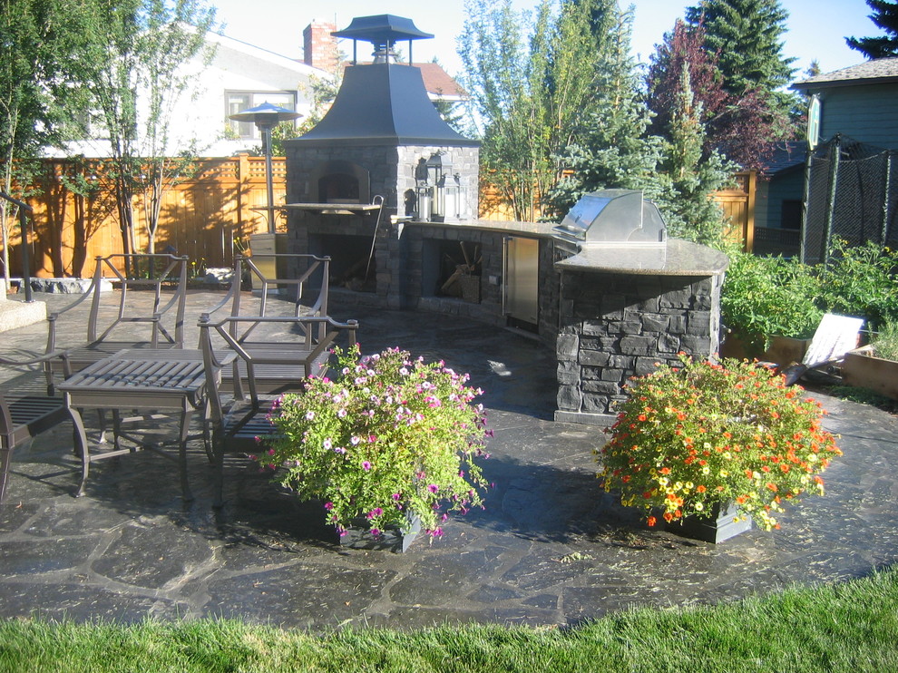 Inspiration for a large traditional backyard patio in Calgary with an outdoor kitchen, natural stone pavers and no cover.
