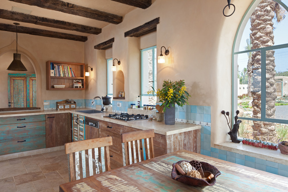 Country eat-in kitchen in Other with flat-panel cabinets, distressed cabinets and blue splashback.