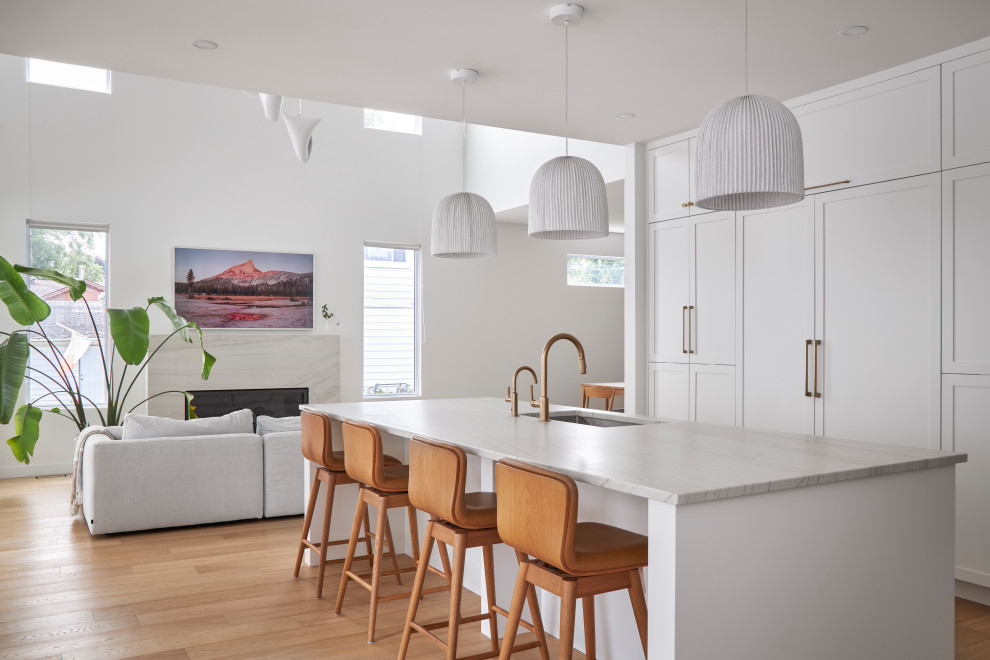 Transitional l-shaped light wood floor eat-in kitchen photo in Ottawa with shaker cabinets, white cabinets, quartzite countertops, white backsplash, ceramic backsplash, paneled appliances and an island