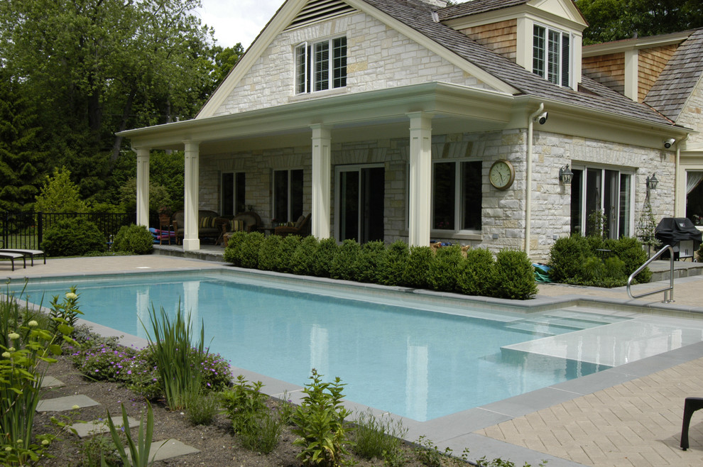 This is an example of a small traditional side yard l-shaped lap pool in Chicago with concrete pavers.