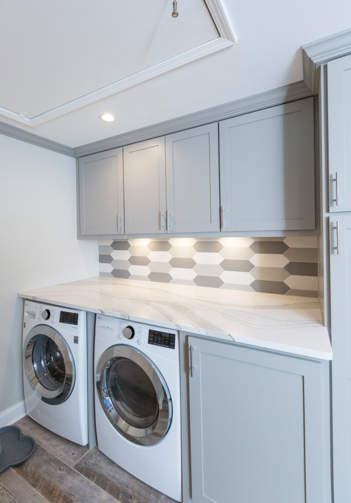 This is an example of a small galley utility room in Cincinnati with an undermount sink, recessed-panel cabinets, grey cabinets, quartz benchtops, multi-coloured splashback, ceramic splashback, grey walls, porcelain floors, a side-by-side washer and dryer, grey floor and white benchtop.