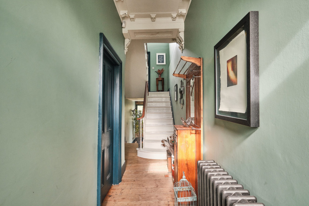 Idee per un corridoio bohémian di medie dimensioni con pareti verdi, pavimento in legno massello medio, una porta singola e una porta nera