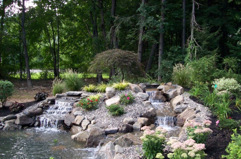 Large country backyard partial sun garden in New York with with pond and gravel.