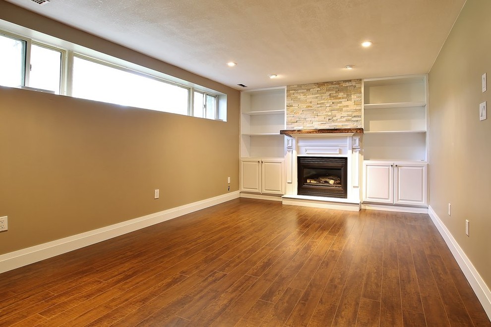Example of a small underground medium tone wood floor basement design with beige walls and a standard fireplace
