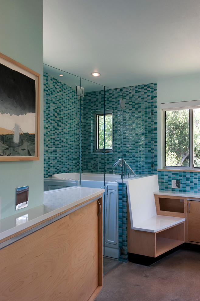 This is an example of a mid-sized contemporary master bathroom in Austin with an undermount sink, flat-panel cabinets, light wood cabinets, engineered quartz benchtops, a curbless shower, a one-piece toilet, blue tile, glass tile, blue walls, concrete floors and a japanese tub.