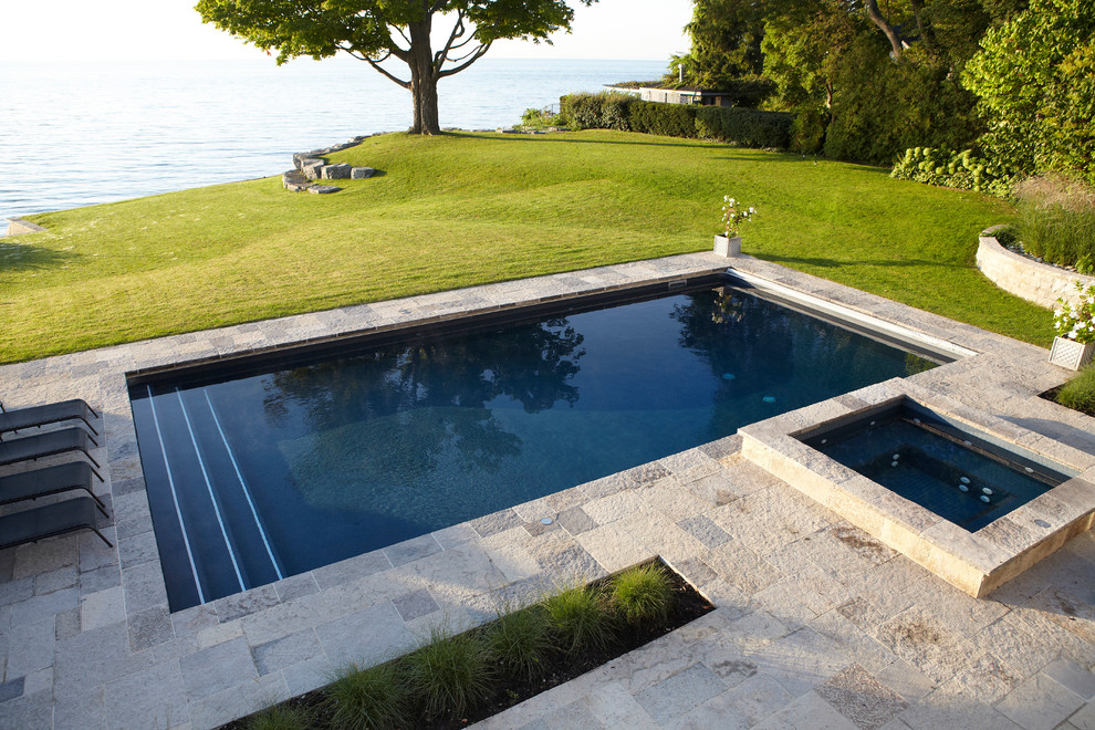 This is an example of a mid-sized traditional backyard rectangular lap pool in Toronto with a hot tub and natural stone pavers.
