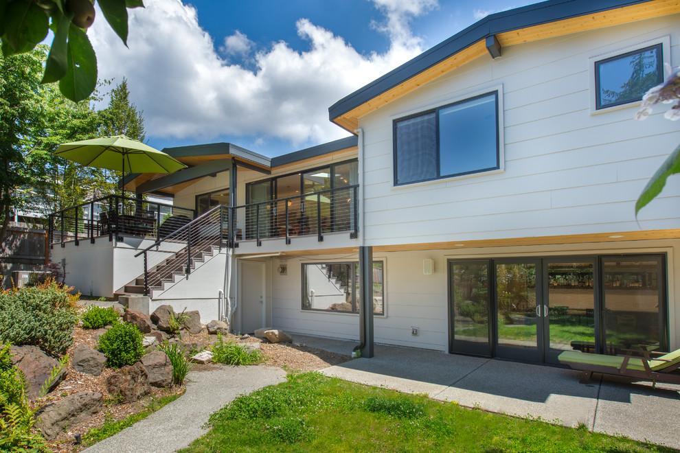 Midcentury two-storey white house exterior in Seattle with vinyl siding and a gable roof.