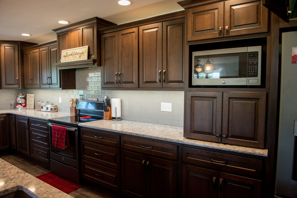 Inspiration for a huge transitional l-shaped medium tone wood floor open concept kitchen remodel with a farmhouse sink, raised-panel cabinets, medium tone wood cabinets, quartz countertops, gray backsplash, subway tile backsplash, stainless steel appliances, an island and multicolored countertops